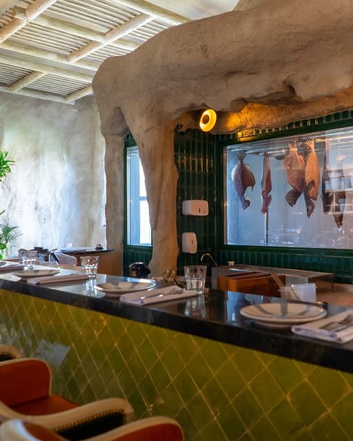 Balcão da cozinha mediterrânea com azulejos verdes, parede caiada em arco e peixes maturando na câmara